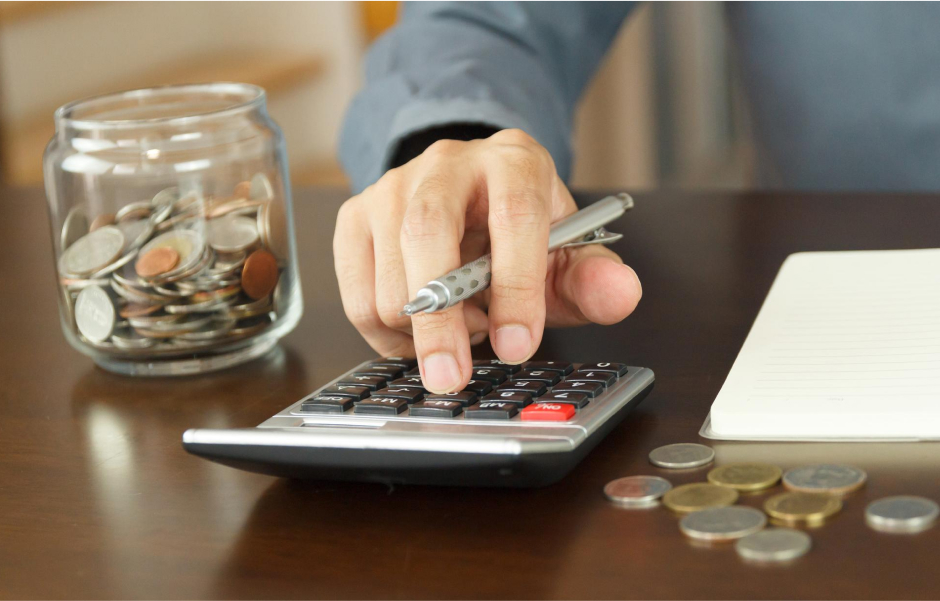 Coins stacked on a calculator, representing the substantial cost savings achieved through outsourcing