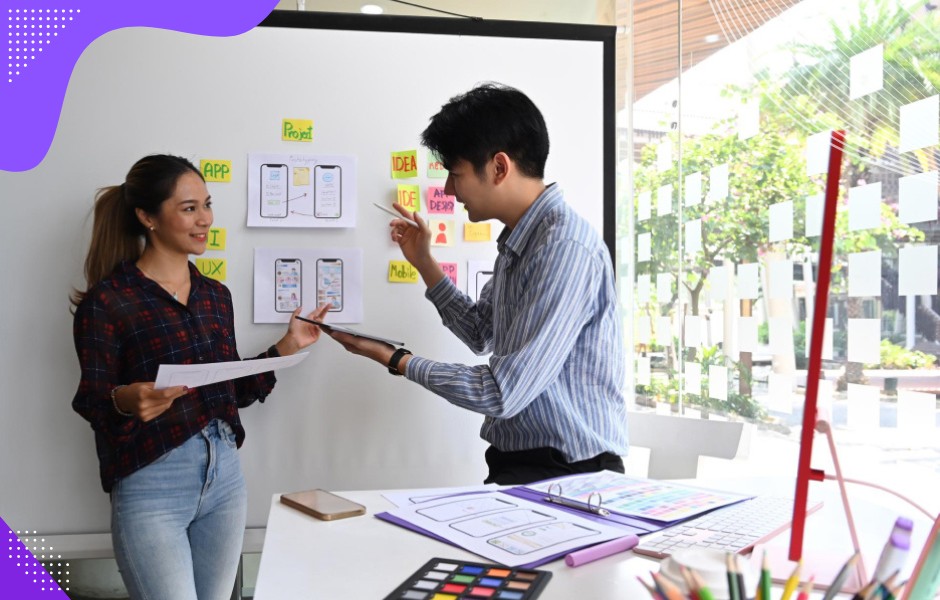 Designers collaborating around a whiteboard to map user journeys and prototype solutions for cross-device experiences.